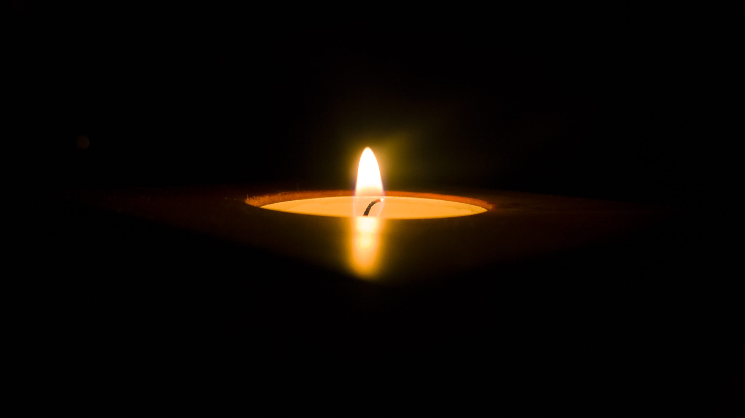 A single lit candle in a dark environment, its flame at the center, gently illuminating the shadows—reflecting the warmth and comfort found at Sholom Senior Living. A single lit candle in a dark environment, its flame at the center, gently illuminating the shadows—reflecting the warmth and comfort found at Sholom Senior Living.