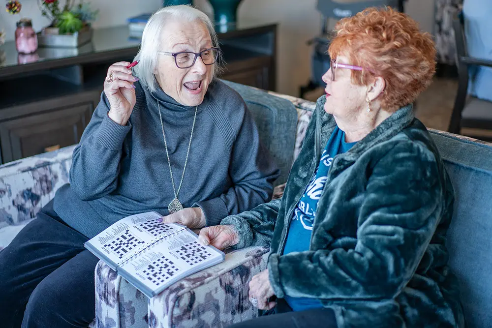 two-bedroom apartment in senior living in st. paul and st. louis park senior lady friends moving into a two-bedroom apartment in senior living together, and laughing playing games